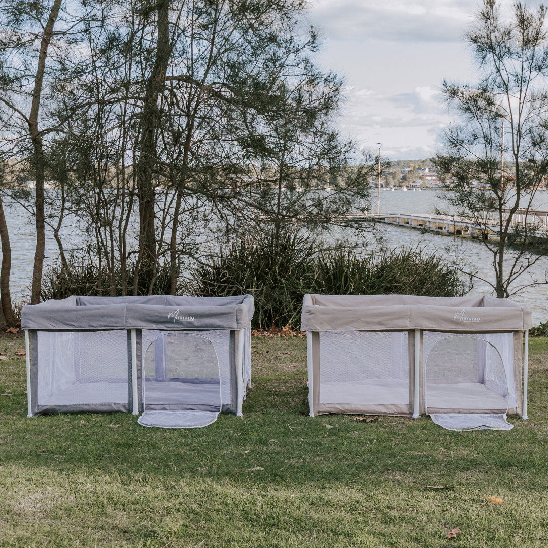 Mummio portable safe space in two colours next to each other. The playpens are grey with a white fame then dune beige with a white frame. Outdoor setup in grass 