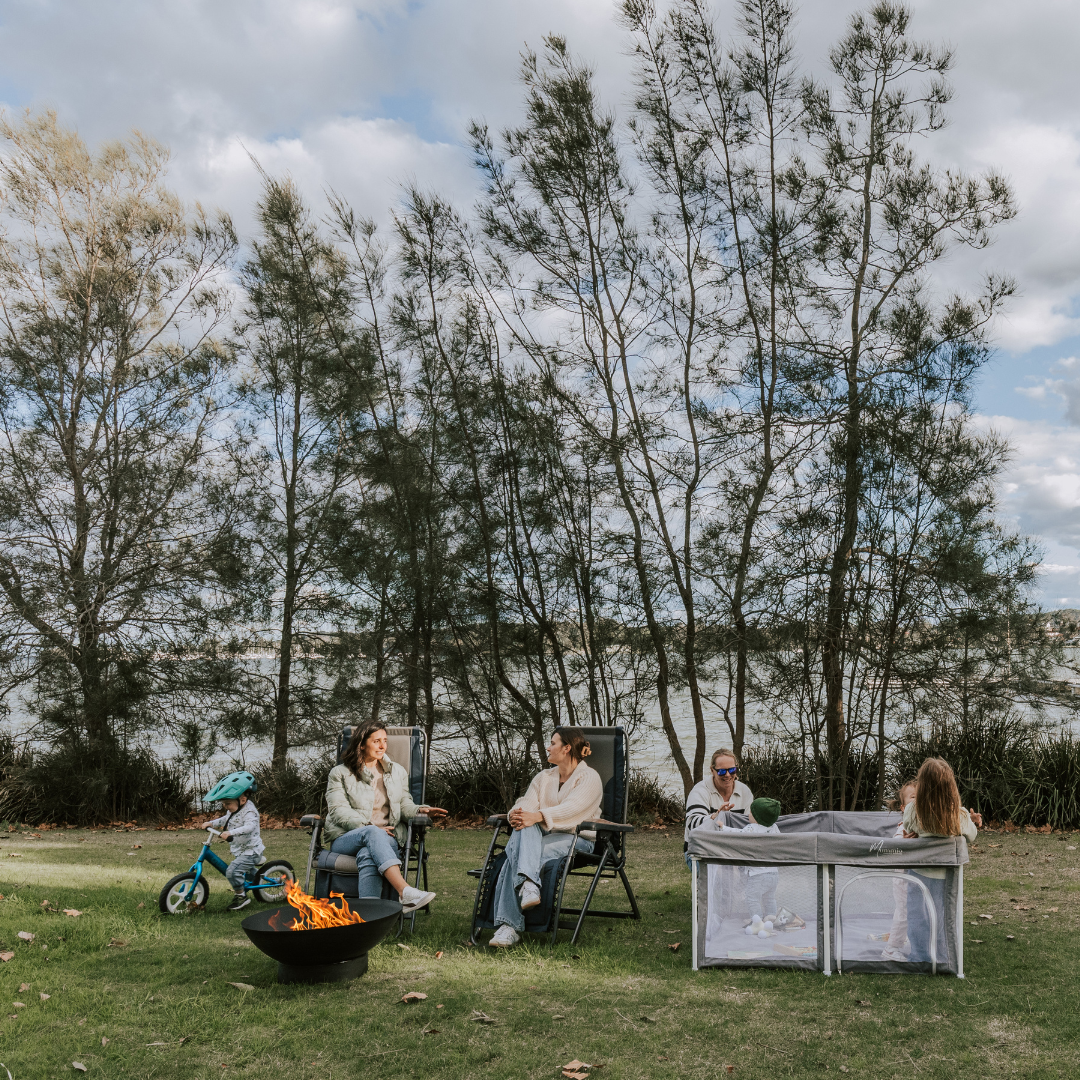 Friends camping with a fire. Kids are happily playing in the grey stone pop up play pen. Safe outdoor play around Fire and Water 